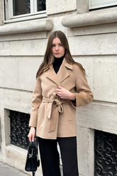 a lady in a wrap cost and a pair of black pants